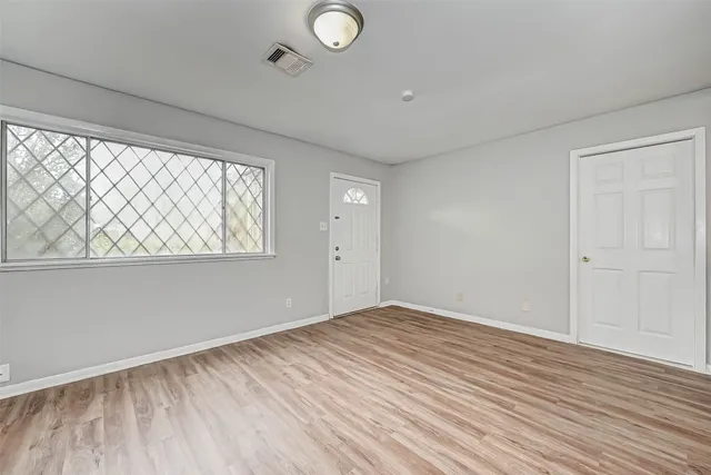 an empty room with wooden floor and windows