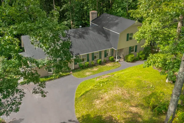 an aerial view of a house with swimming pool and large trees