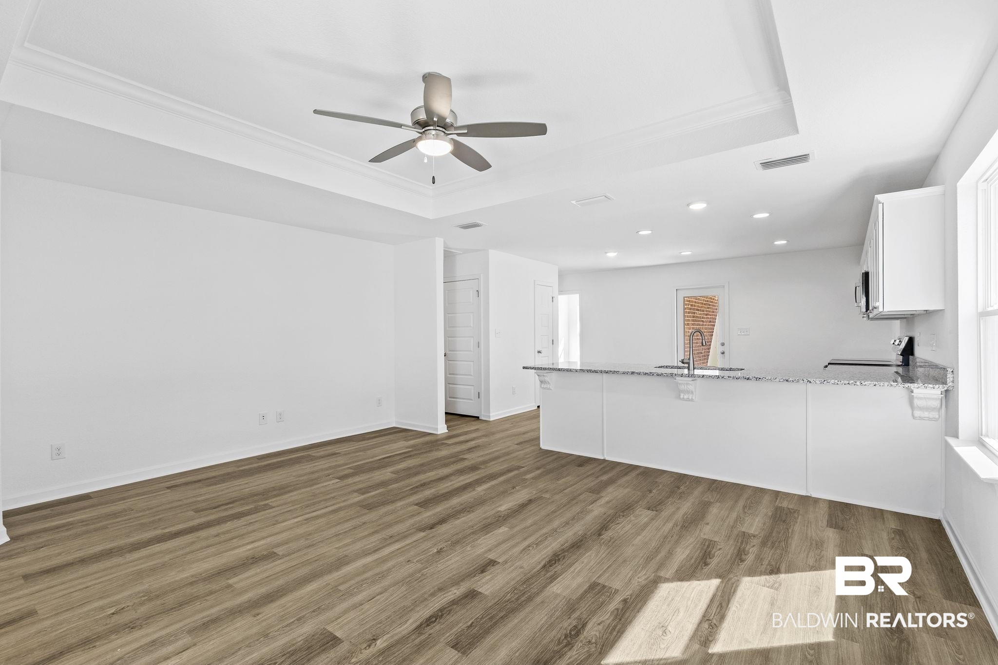 16014 Alabama Avenue Silverhill, AL 36576 - Photo 10 of 50 Unfurnished living room featuring crown molding, ceiling fan, dark hardwood / wood-style floors, and a raised ceiling