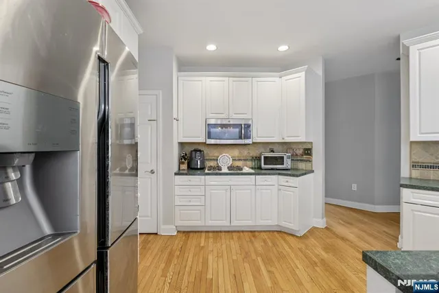 a kitchen with stainless steel appliances granite countertop a refrigerator a stove and a sink