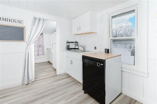 a kitchen with stainless steel appliances granite countertop a refrigerator a sink and white cabinets