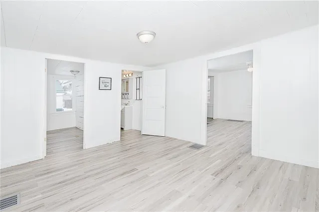 an empty room with wooden floor & windows