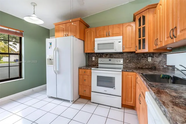 a kitchen with stainless steel appliances a sink a stove a refrigerator and cabinets
