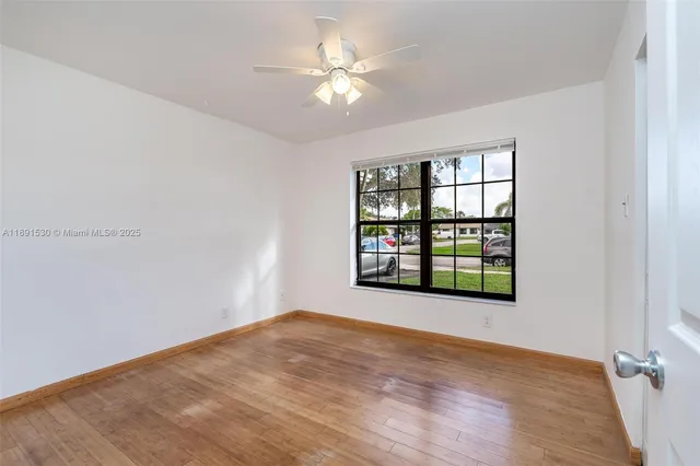 a view of empty room with wooden floor and fan