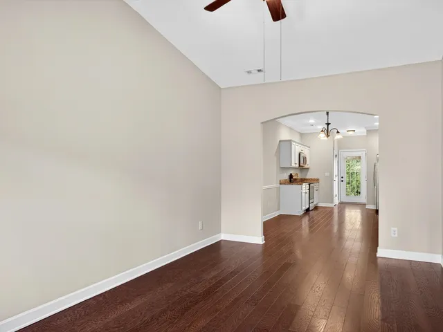 a view of a kitchen with wooden floor a ceiling fan and windows