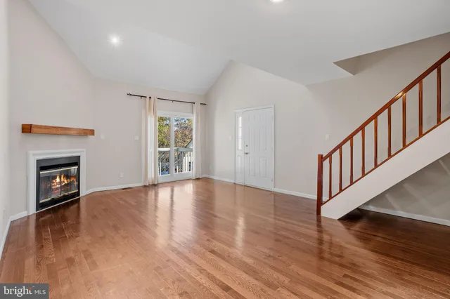 a view of an empty room with wooden floor fireplace and a window