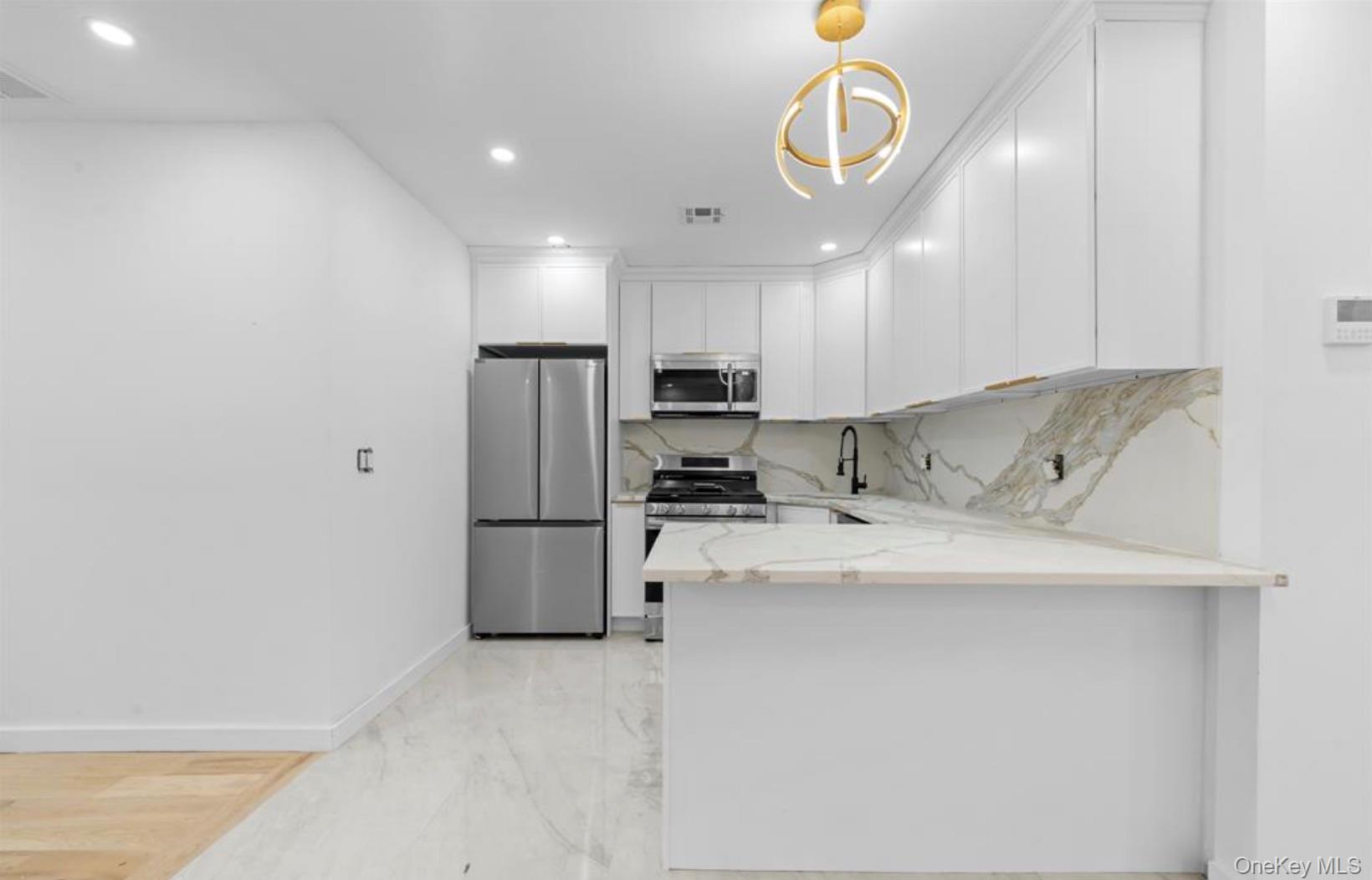 752 Lenox Road Brooklyn, NY 11203 - Photo 9 of 14 Kitchen featuring appliances with stainless steel finishes, light stone counters, white cabinets, tasteful backsplash, and light marble finish floors