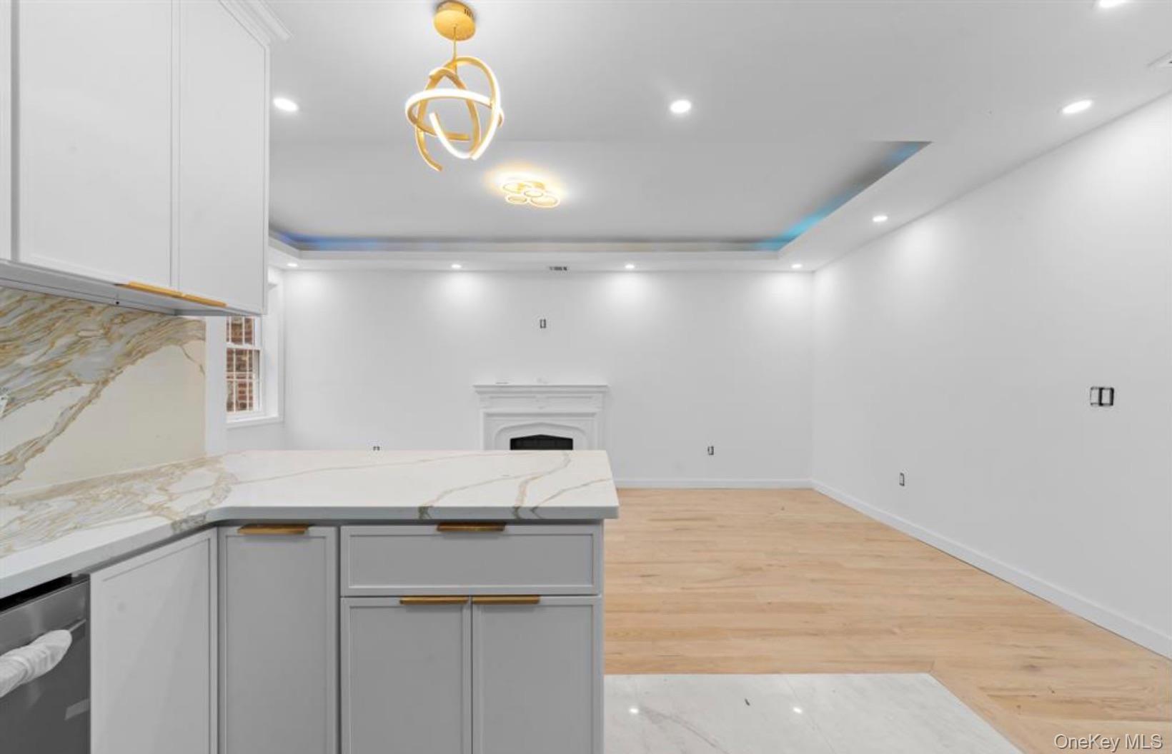 752 Lenox Road Brooklyn, NY 11203 - Photo 10 of 14 Kitchen featuring pendant lighting, recessed lighting, light stone counters, light wood-style floors, and a tray ceiling