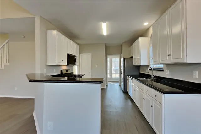 a kitchen with stainless steel appliances a sink a stove a microwave a sink a refrigerator and cabinets