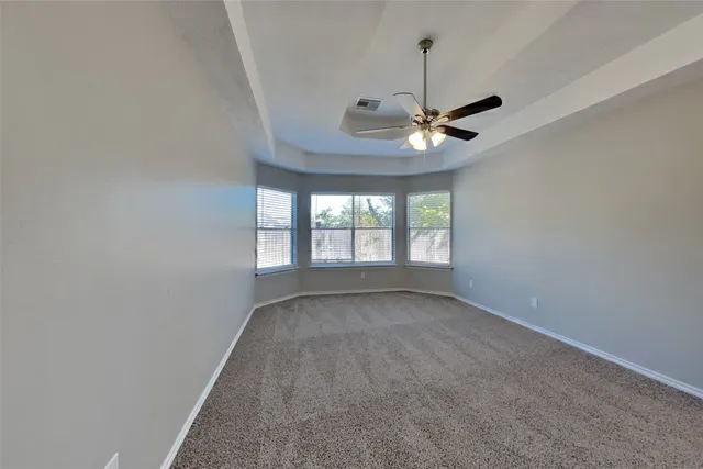 an empty room with chandelier fan and windows