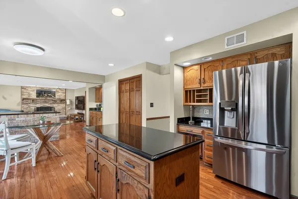 a kitchen with stainless steel appliances granite countertop a table chairs and a refrigerator