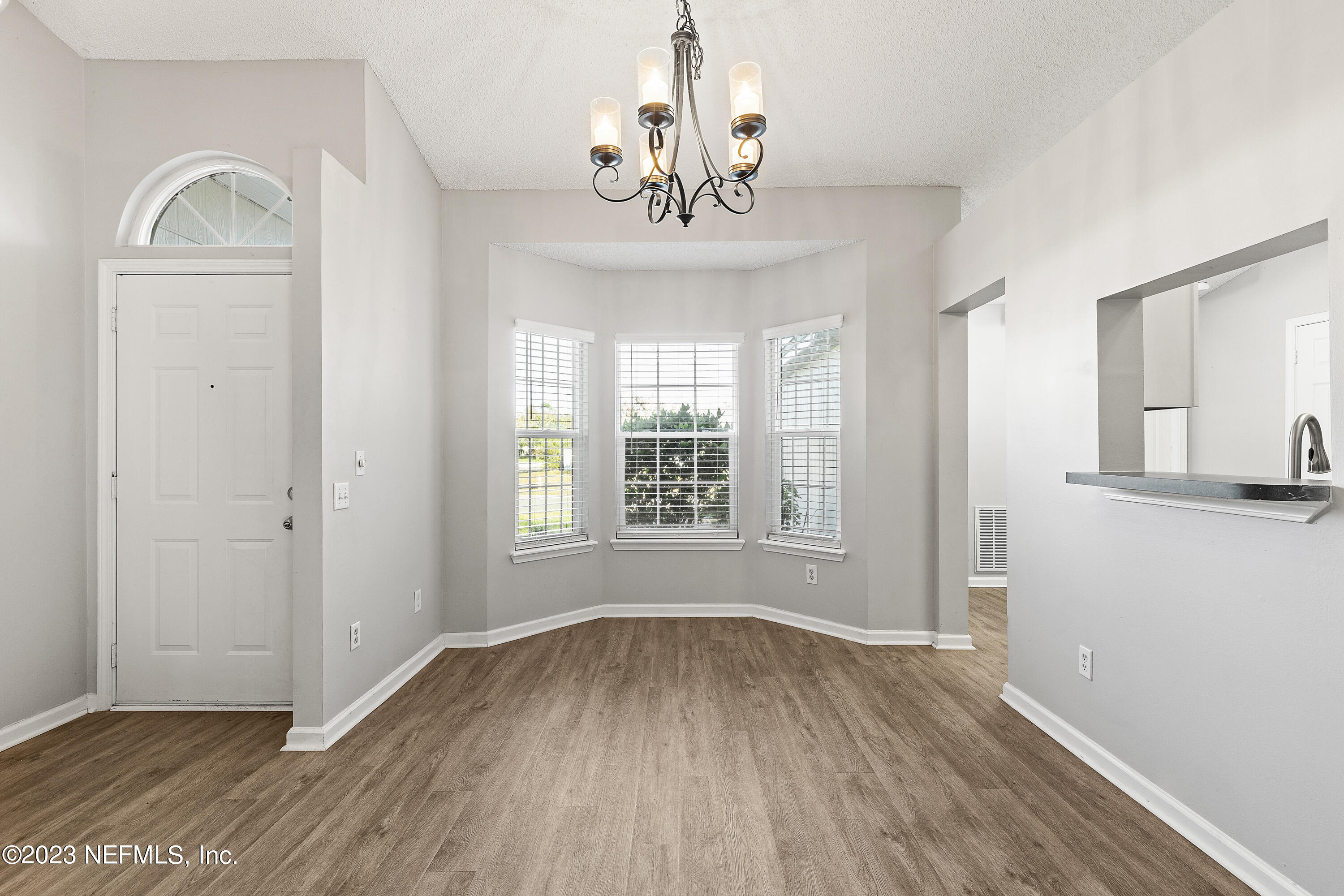 13240 Pacemaker Drive Jacksonville, FL 32225 - Photo 4 of 21 an empty room with wooden floor chandelier and windows