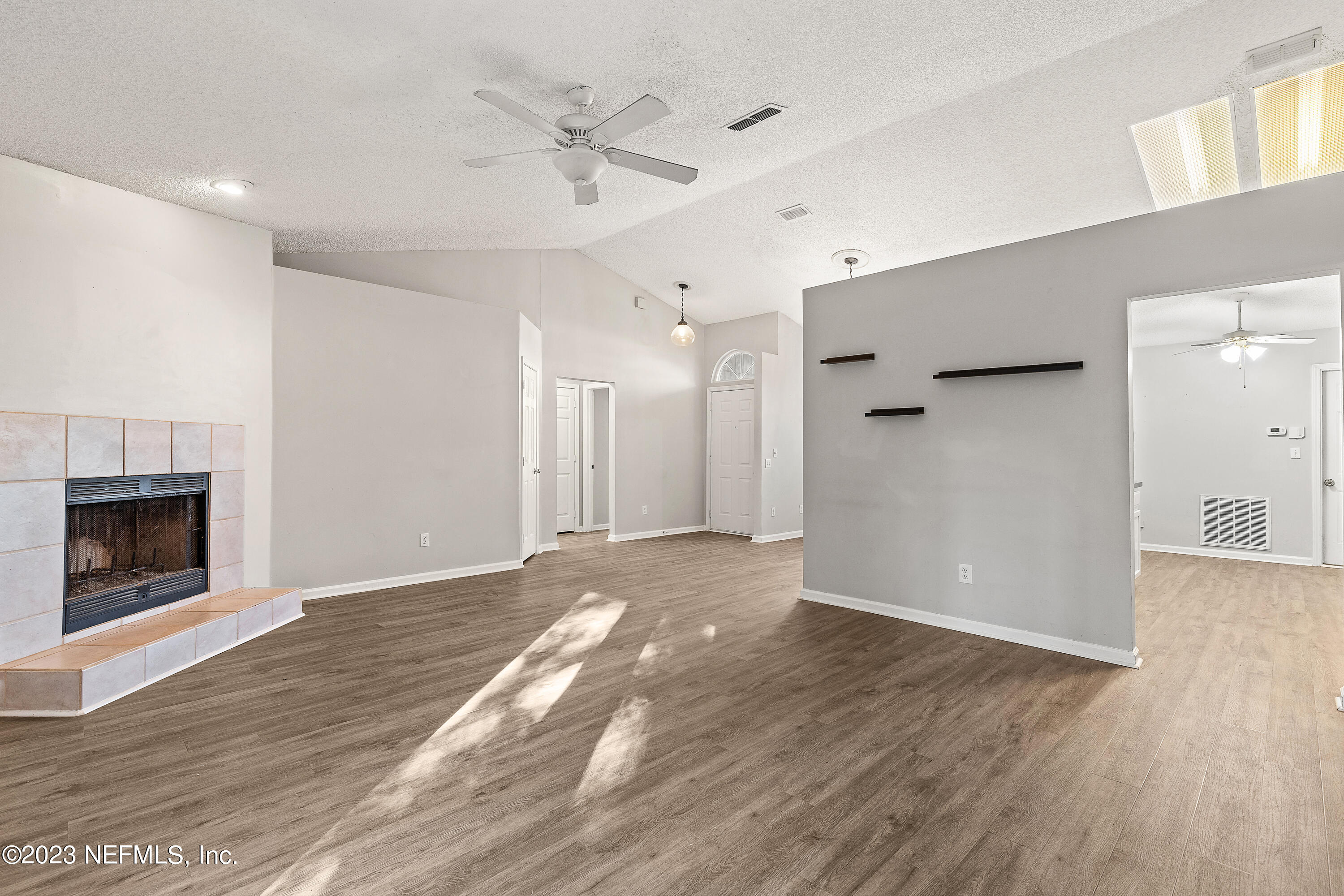 13240 Pacemaker Drive Jacksonville, FL 32225 - Photo 8 of 21 a view of an empty room with wooden floor a fireplace and a window