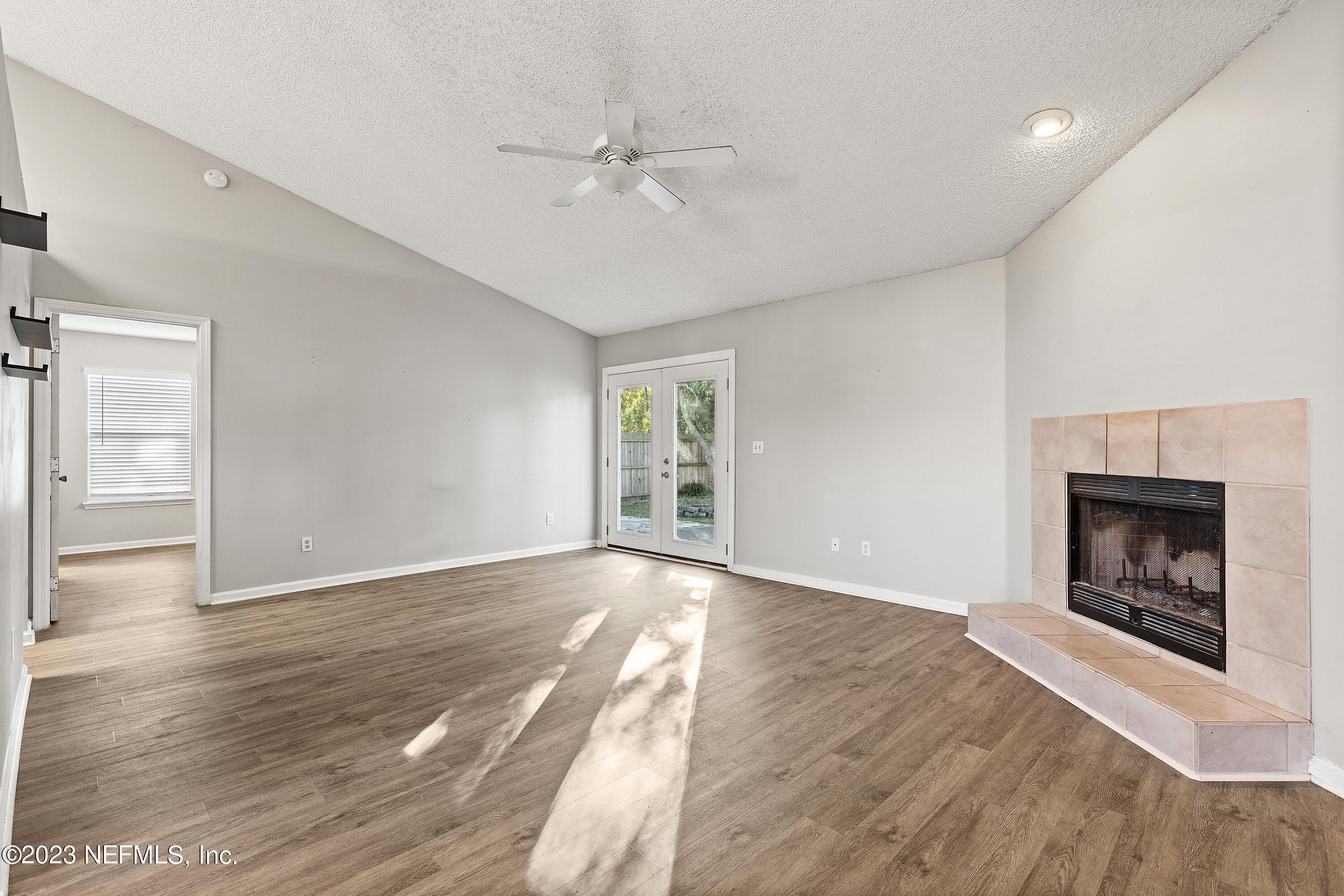 13240 Pacemaker Drive Jacksonville, FL 32225 - Photo 9 of 21 an empty room with wooden floor fireplace and windows