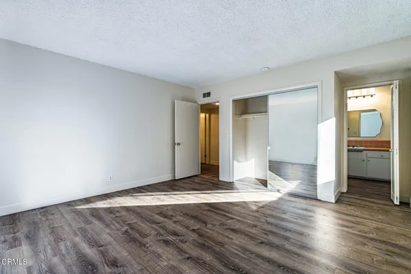 a view of a livingroom with wooden floor and kitchen space