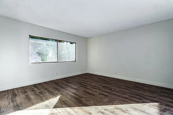 a view of an empty room with wooden floor and window