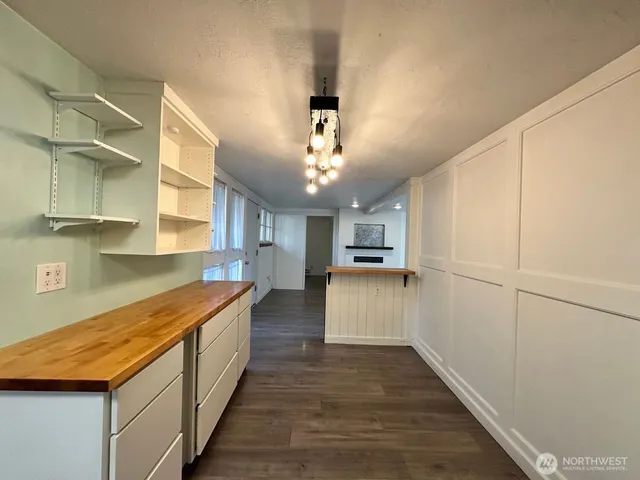 a view of a kitchen with kitchen island a sink wooden floor and stainless steel appliances