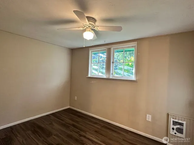 an empty room with wooden floor fan and windows