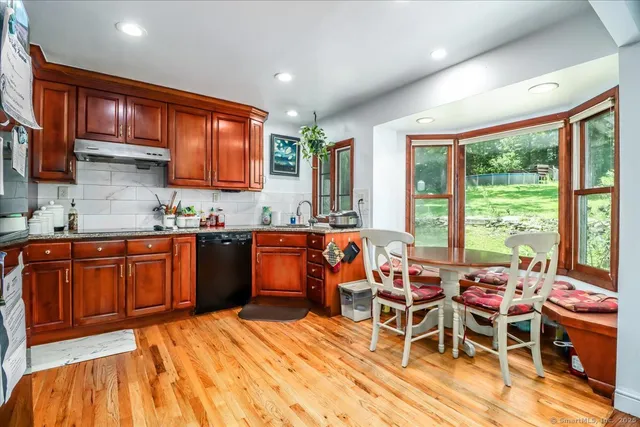 a kitchen with stainless steel appliances kitchen island granite countertop a table chairs in it and wooden floors