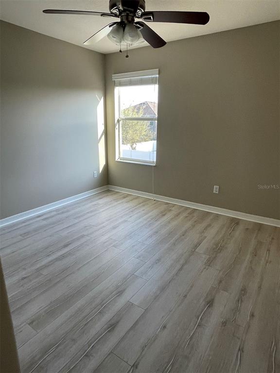 12016 Deer Path Way Orlando, FL 32832 - Photo 28 of 38 an empty room with wooden floor chandelier fan and windows