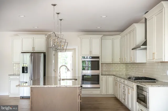 a kitchen with stainless steel appliances granite countertop a sink a refrigerator and a granite counter tops