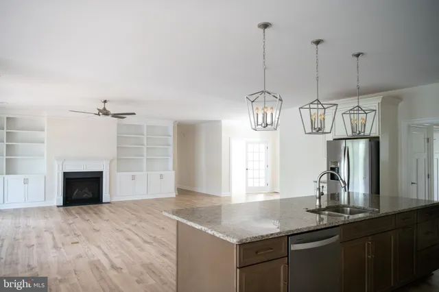a kitchen with stainless steel appliances granite countertop a sink a refrigerator and a wooden floor