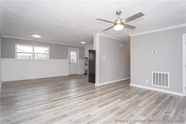 a view of an empty room with wooden floor and a ceiling fan
