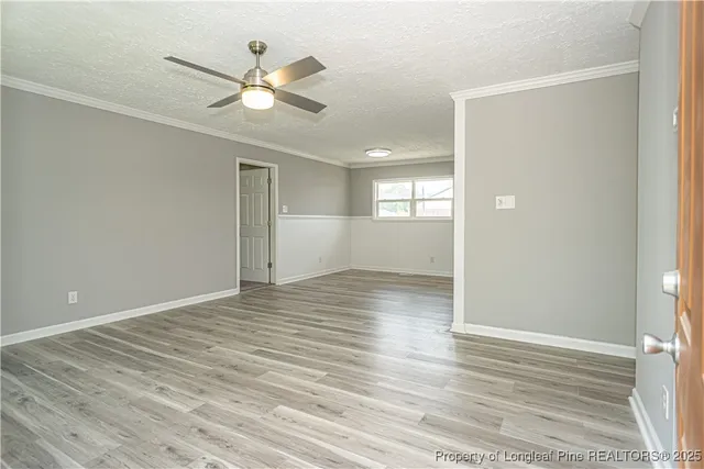 a view of an empty room with wooden floor and a ceiling fan