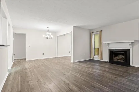 a view of an empty room with wooden floor fireplace and a window