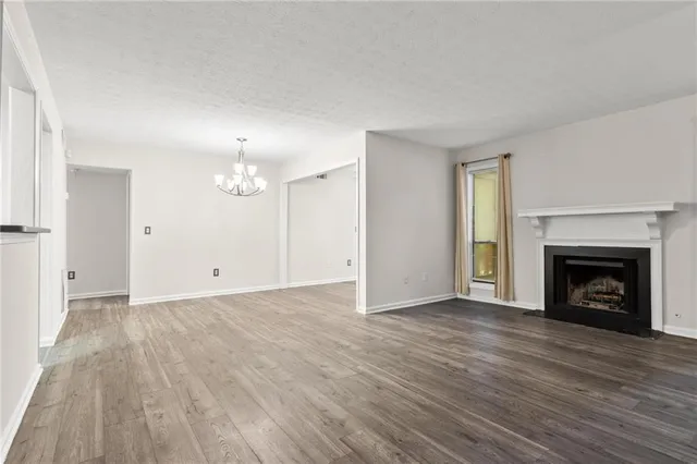 a view of an empty room with wooden floor fireplace and a window