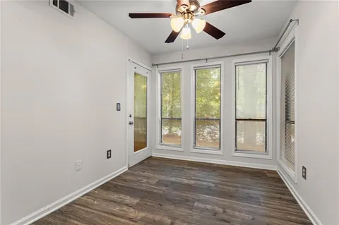 a view of an empty room with a window and wooden floor