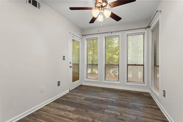 a view of an empty room with a window and wooden floor