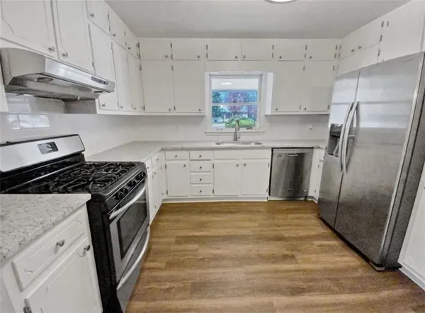 a kitchen with white cabinets and appliances