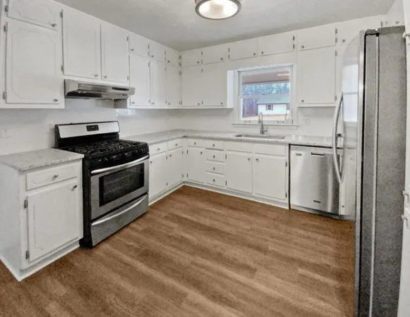 a kitchen with granite countertop white cabinets and white stainless steel appliances