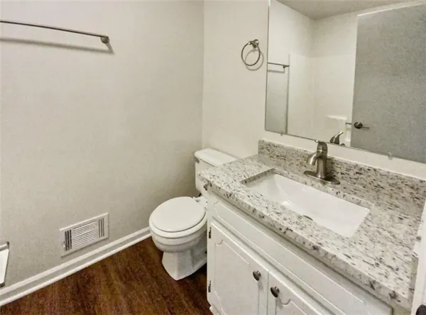 a bathroom with a granite countertop sink a toilet and a mirror