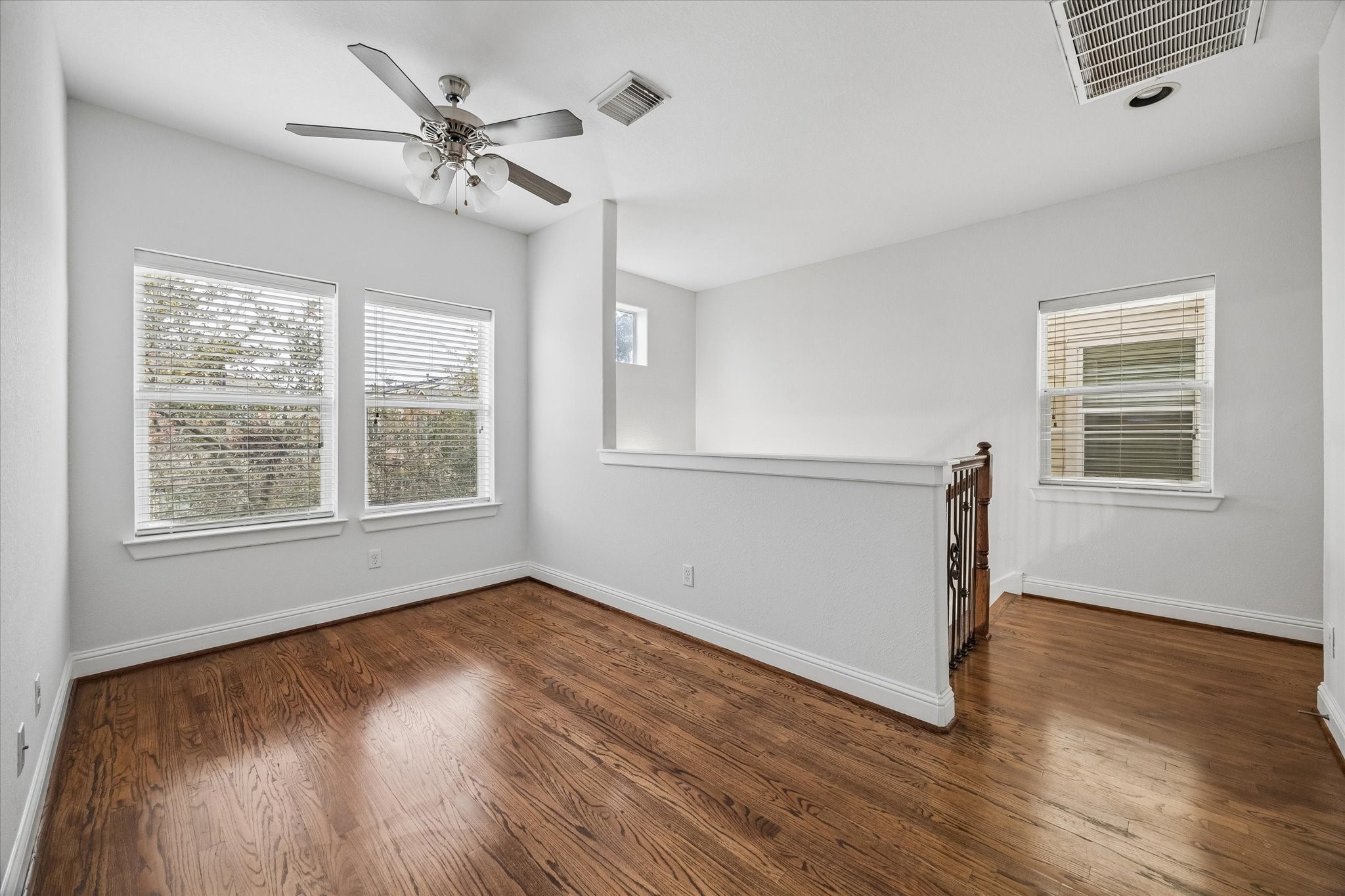 1033 West 23rd Street Houston, TX 77008 - Photo 21 of 25 an empty room with wooden floor chandelier fan and windows