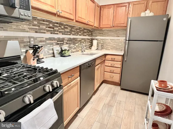 a kitchen with granite countertop a refrigerator a stove and wooden floor