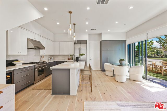 a large kitchen with a large counter top a sink stainless steel appliances and cabinets