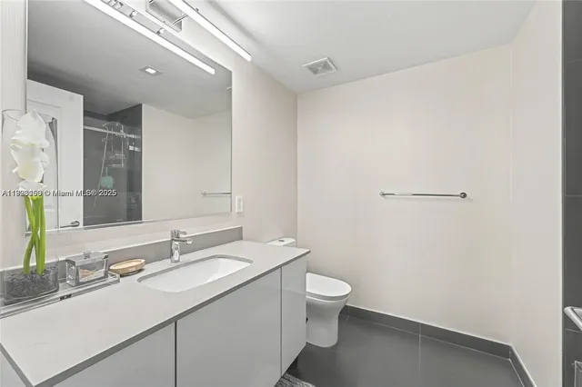 a bathroom with a granite countertop sink a toilet and a mirror