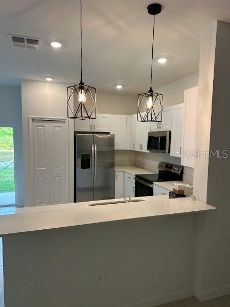 212 27th Street Southeast Ruskin, FL 33570 - Photo 11 of 46 a kitchen with stainless steel appliances a stove a refrigerator a sink and a fireplace