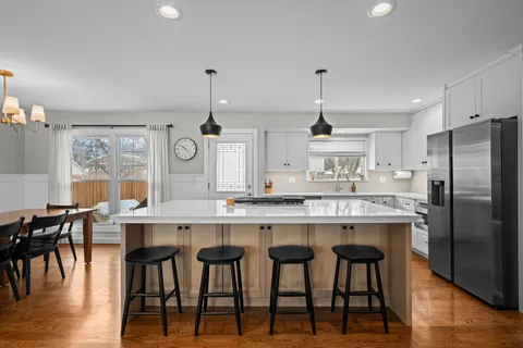 a kitchen with kitchen island granite countertop a table chairs stove and wooden floor