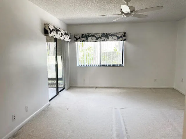 an empty room with a window and a fan