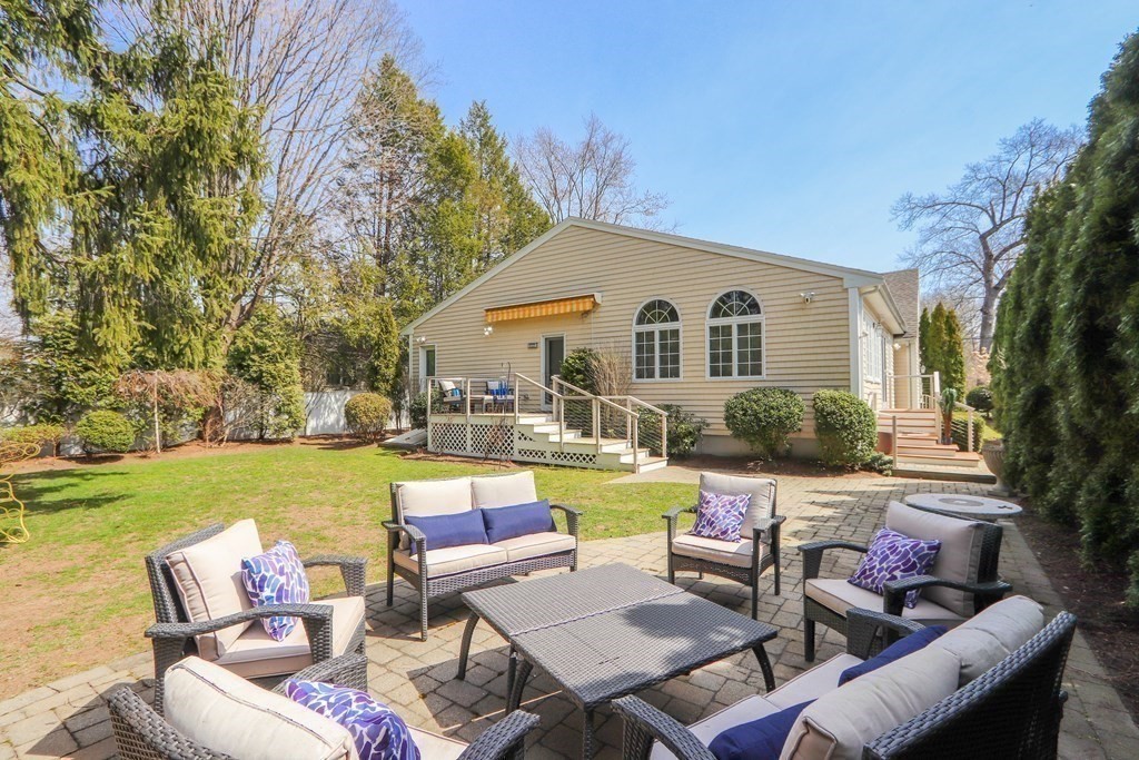 325 Manning Street Needham, MA 02492 - Photo 31 of 31 a view of a patio with couches and a table and chairs under an umbrella with large trees