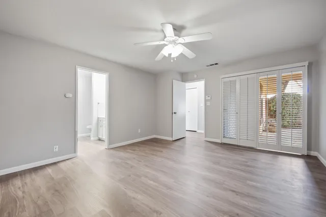 an empty room with wooden floor and windows