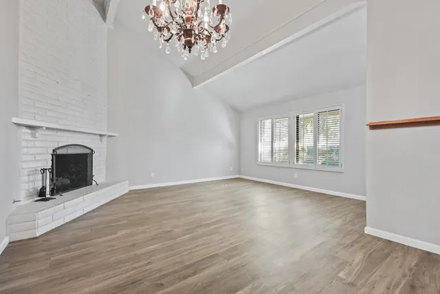 a view of a livingroom with a fireplace a chandelier and wooden floor