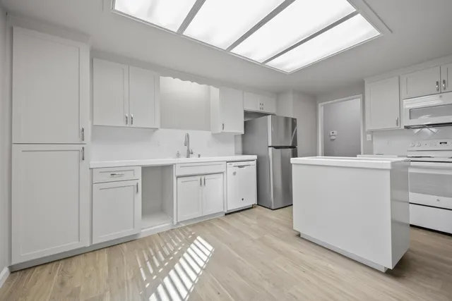a kitchen with white cabinets and white appliances