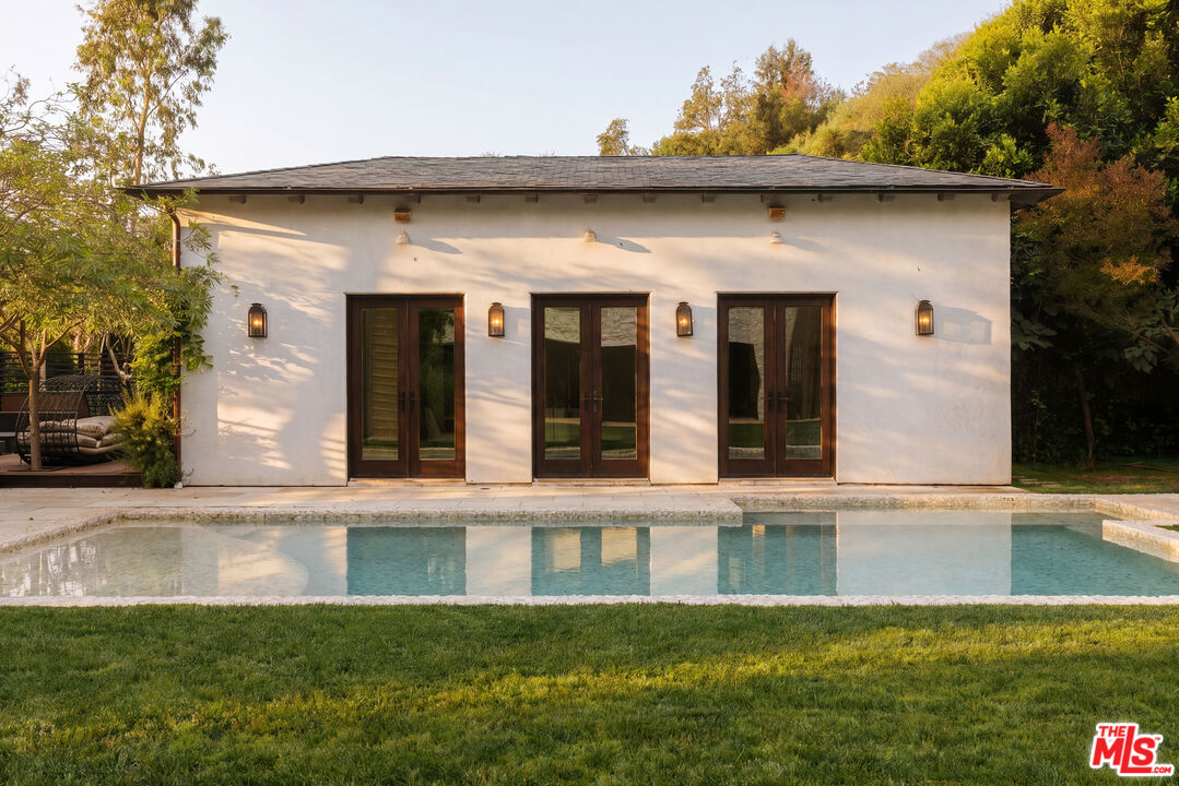 1105 Rivas Canyon Road Pacific Palisades, CA 90272 - Photo 45 of 49 a view of a white house with a large window and a yard with plants and large trees