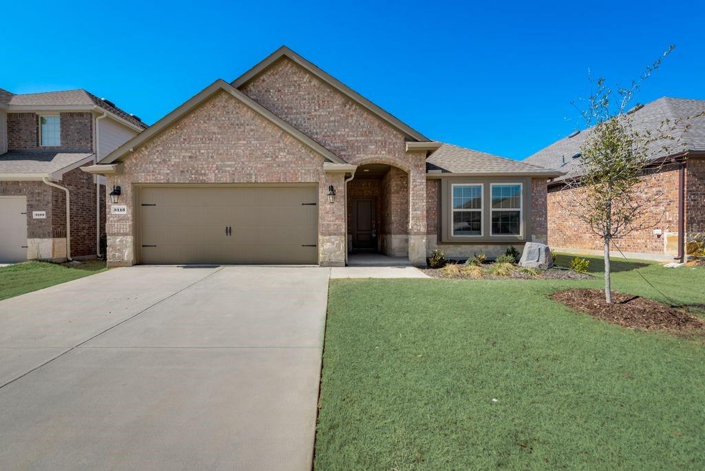 View of front facade featuring brick siding, a front yard, concrete driveway, and a garage