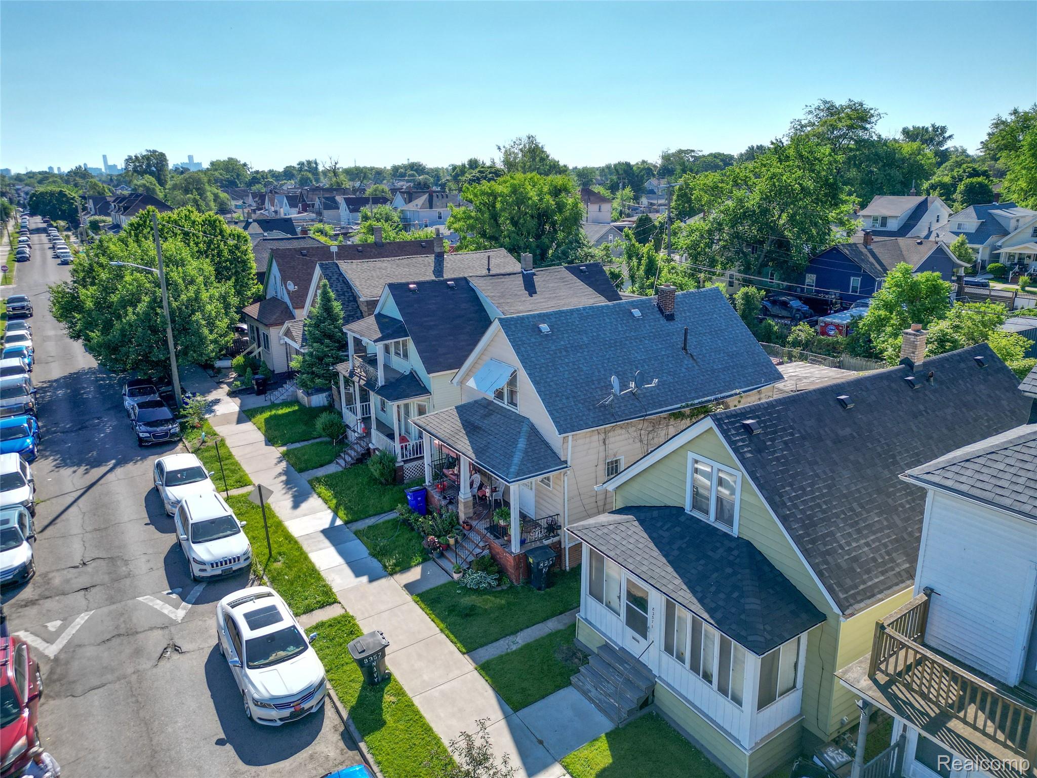 8357 Navy Street Detroit, MI 48209 - Photo 25 of 26 Residential streetscape featuring a row of single-family homes with pitched roofs, front porches, and mature trees lining the street