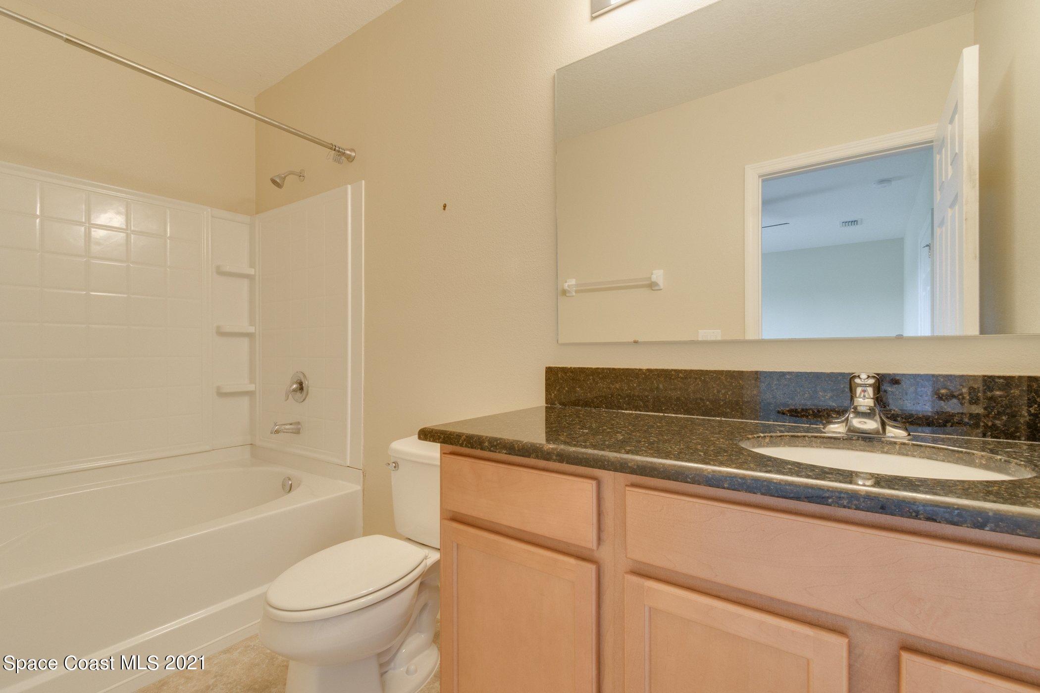 2780 Reston Street, Unit 102 Melbourne, FL 32935 - Photo 21 of 36 a bathroom with a granite countertop sink toilet mirror and bathtub